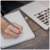 Stock image of someone writing next to laptop