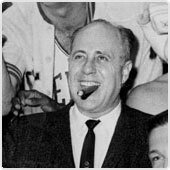 Boston Celtics coach Red Auerbach smiling while holding a victory cigar