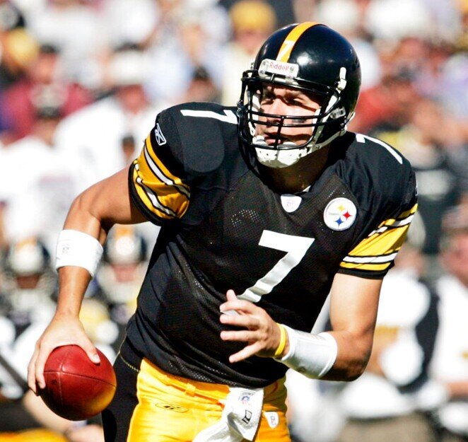 Pittsburgh Steelers quarterback in a black jersey with number 7 prepares to throw a football during a game, holding the ball in his right hand while looking downfield