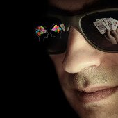 Man with shades and poker cards reflecting in glasses