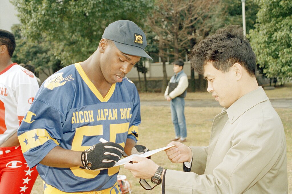 Alabama linebacker Derrick Thomas gives his autograph to a Japanese football fan