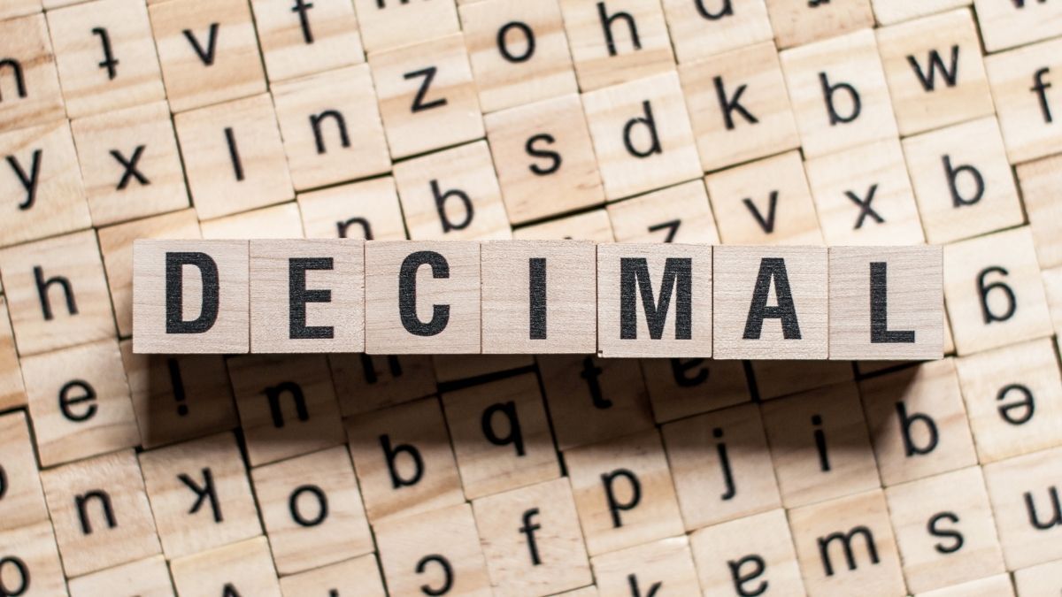 Wooden letter tiles spelling the word ‘DECIMAL’ on a background of scattered alphabet tiles