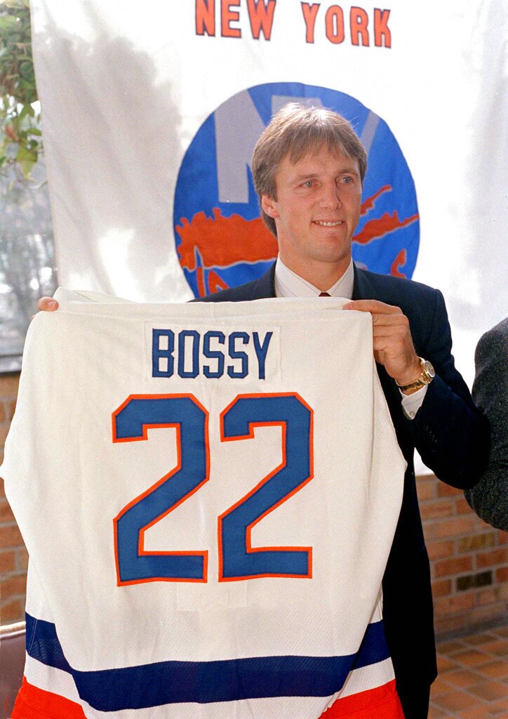 Mike Bossy holds his New York Islanders uniform up at a news conference