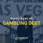 Bruno Mars performing on stage in front of a Las Vegas sign with text overlay “Bruno Mars on Gambling Debt” and GamblingSites.com branding