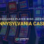 Slot machines inside a casino with text reading Self-Excluded Player Wins Jackpot at Pennsylvania Casino