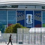FIFA World Cup 2026 signage displayed on the exterior of a stadium, with security fencing and a pedestrian in the foreground.