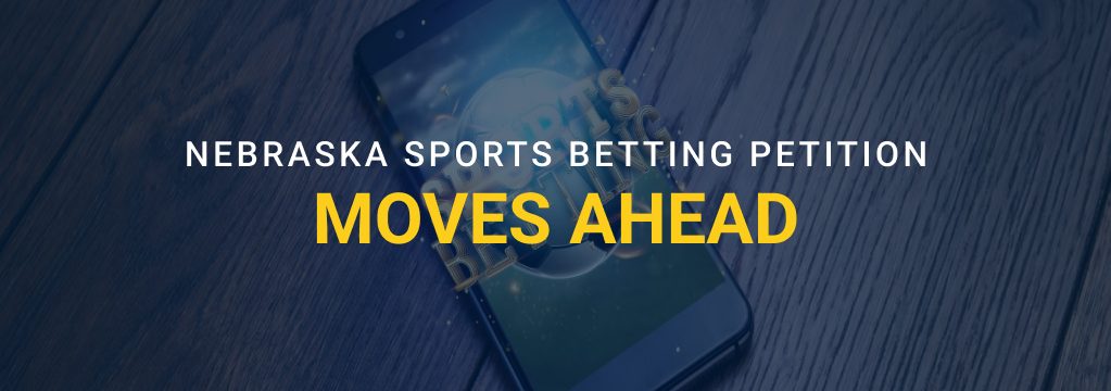 Smartphone on a wooden surface with overlaid text reading “Nebraska Sports Betting Petition Moves Ahead” and the GamblingSites.com logo.